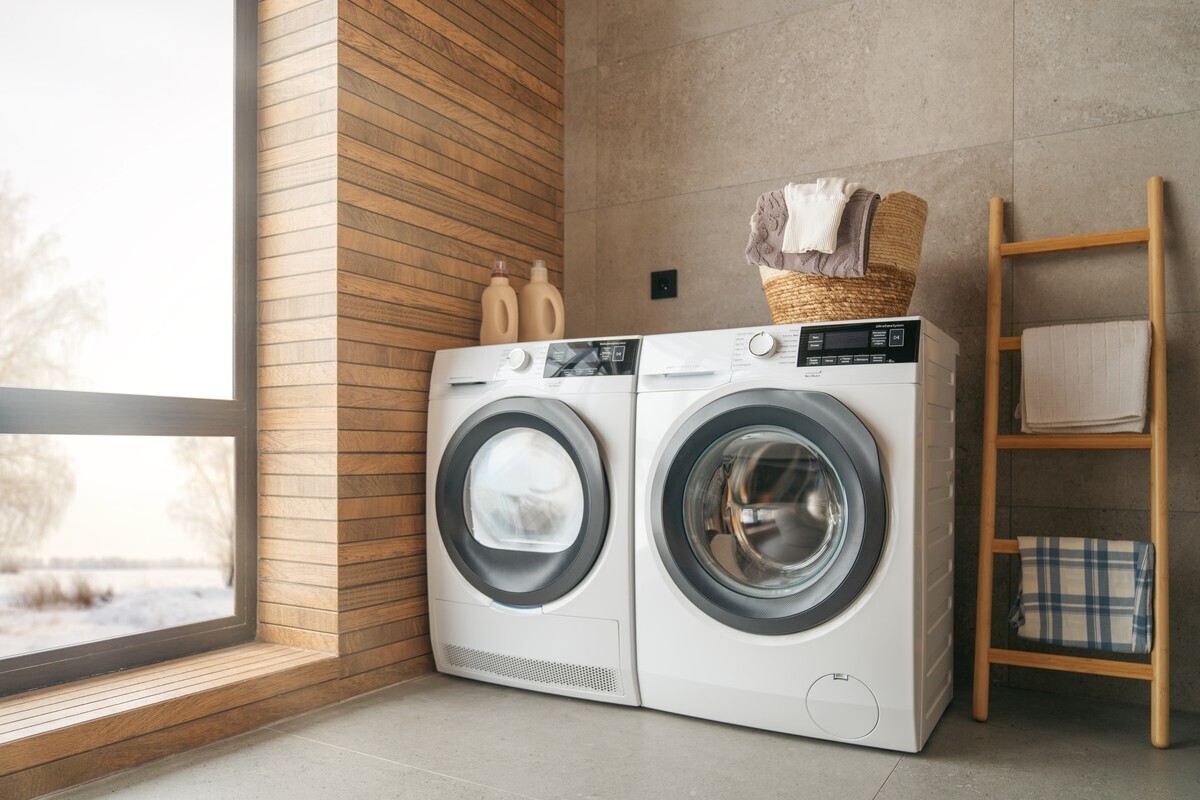 Washing machine and tumble dryer side by side in a bright utility room with a laundry basket
